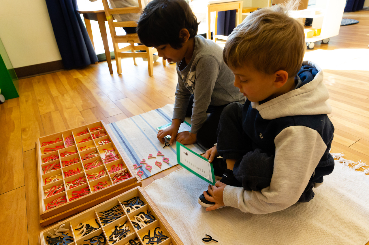 Children writing using wooden cursive letters in a primary Montessori Classroom in San Diego