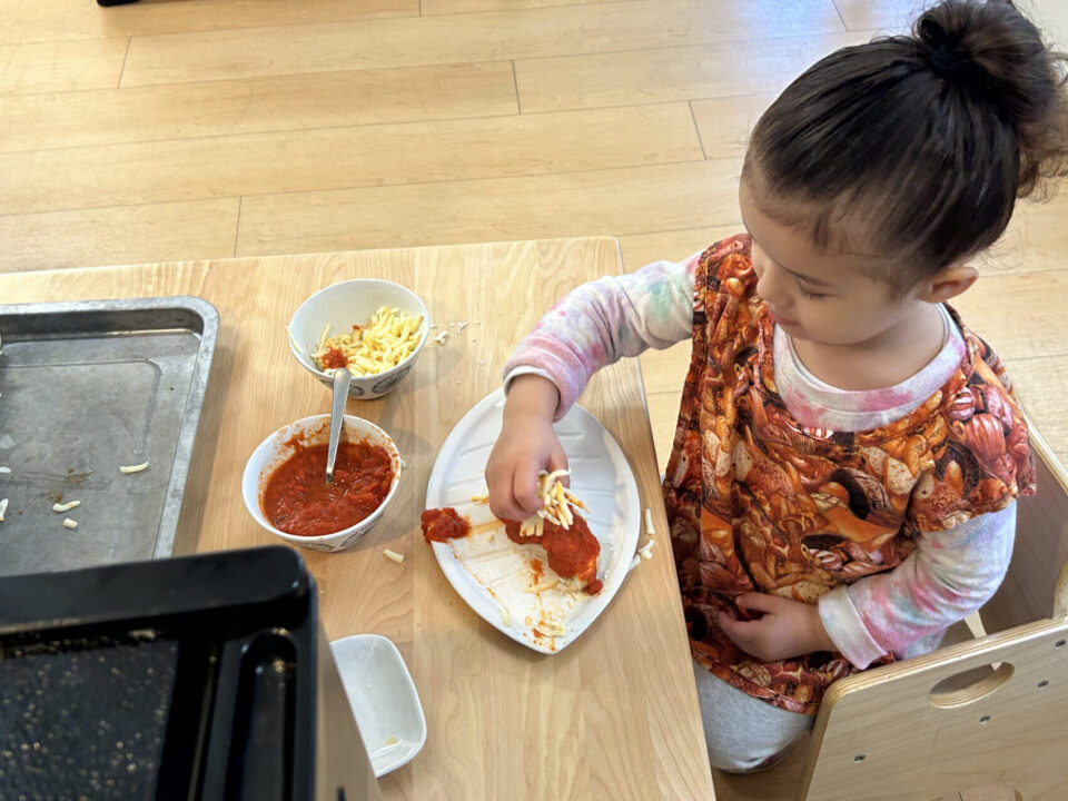 Independence in Toddlers, child making pizza independently at Shadowridge Montessori School