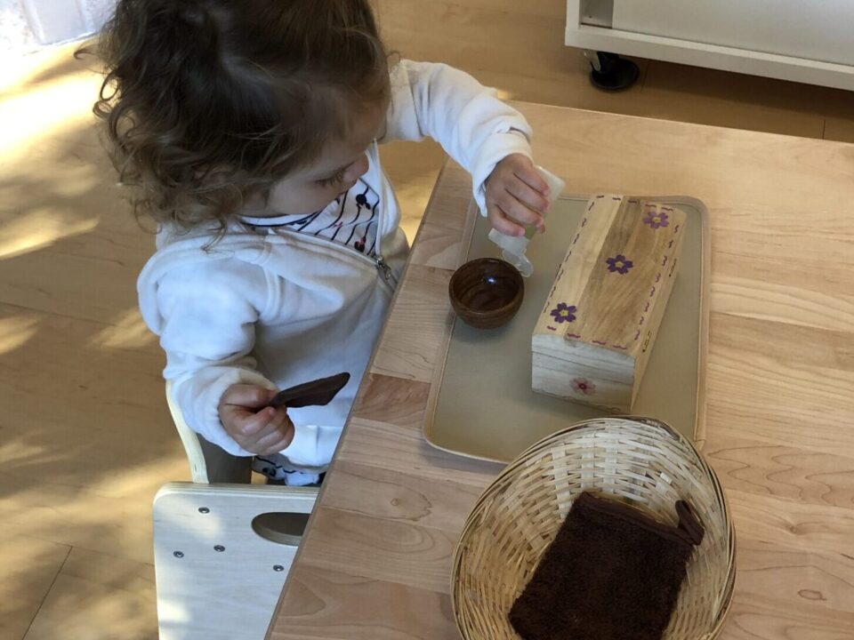 Montessori toddler squirting liquid into a small bowl