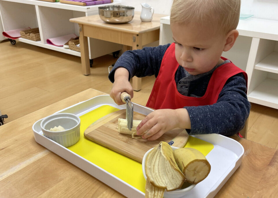 Toddler cutting bananas independently at Shadowridge Montessori School