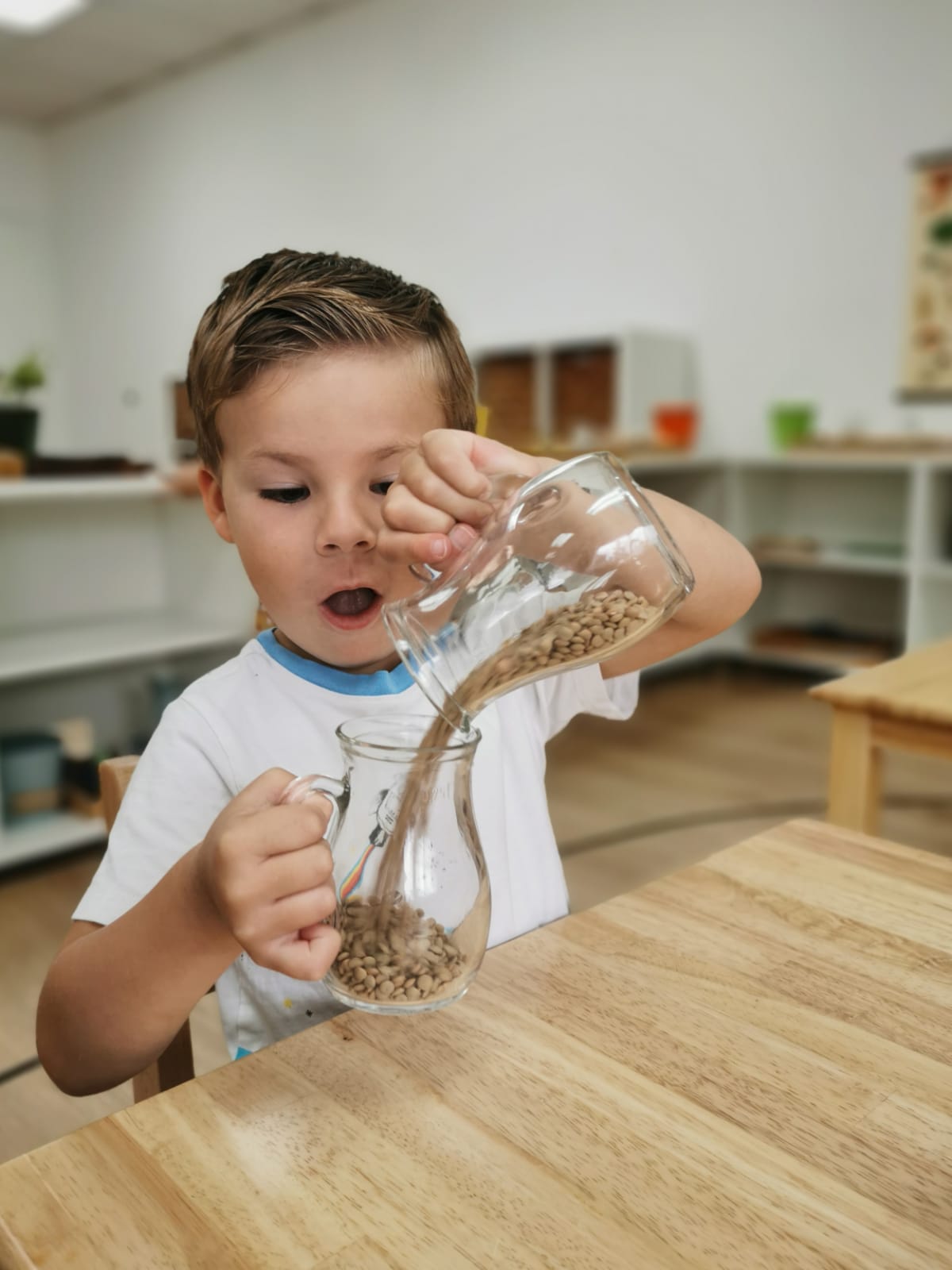 Primary child at Educational Preschool at Shadowridge Montessori School Pouring beans into jar