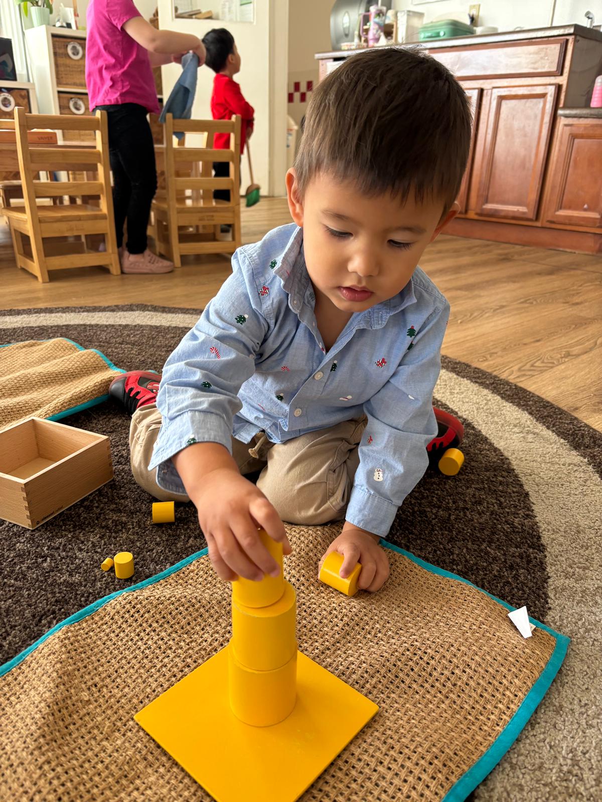 Shadowridge Montessori School student working with yellow cylinder blocks during a hands-on sensorial math lesson